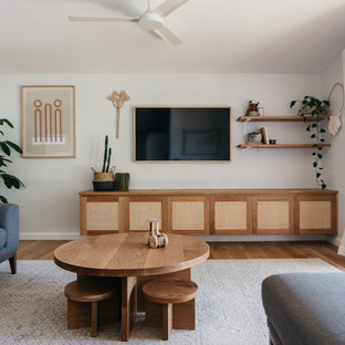 Design ideas for a mid-sized beach style family room in Central Coast with white walls, light hardwood floors, no fireplace and a wall-mounted tv.