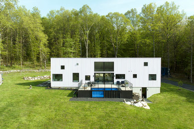 Mid-sized 1950s one-story house exterior idea in New York with a shed roof, a metal roof and a white roof