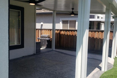 Ejemplo de patio moderno de tamaño medio en patio trasero con losas de hormigón y toldo