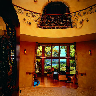 Bild på en stor eklektisk foajé, med bruna väggar, klinkergolv i terrakotta, mörk trädörr och orange golv