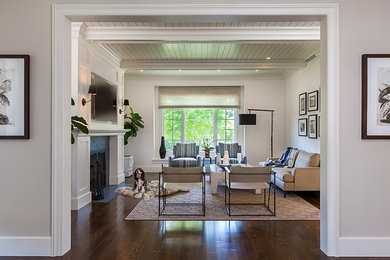 Large transitional enclosed medium tone wood floor family room photo in Detroit with beige walls, a standard fireplace, a stone fireplace and a wall-mounted tv