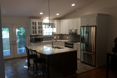 Inspiration for a contemporary l-shaped ceramic tile kitchen remodel in Chicago with an undermount sink, raised-panel cabinets, white cabinets, quartzite countertops, gray backsplash, ceramic backsplash, stainless steel appliances and an island