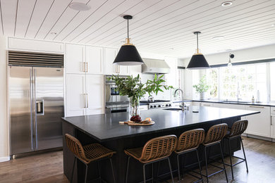 Inspiration for a large contemporary l-shaped brown floor and shiplap ceiling eat-in kitchen remodel in San Francisco with beaded inset cabinets, white cabinets, soapstone countertops, white backsplash, stone tile backsplash, stainless steel appliances, an island and black countertops