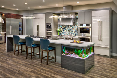 Large trendy single-wall vinyl floor and brown floor eat-in kitchen photo in Sacramento with flat-panel cabinets, gray cabinets, quartz countertops, blue backsplash, glass tile backsplash, stainless steel appliances, an island and white countertops