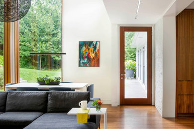 Foto de salón abierto contemporáneo con paredes blancas, suelo de madera en tonos medios y suelo marrón