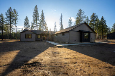Inspiration for a brown one-story board and batten house exterior remodel in Other with a black roof
