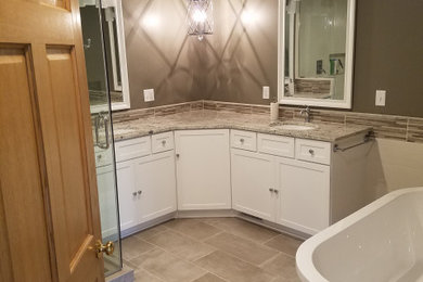 Bathroom - large contemporary master brown tile and stone tile porcelain tile, brown floor and double-sink bathroom idea in Milwaukee with shaker cabinets, white cabinets, a two-piece toilet, brown walls, an undermount sink, granite countertops, a hinged shower door, brown countertops, a niche and a built-in vanity