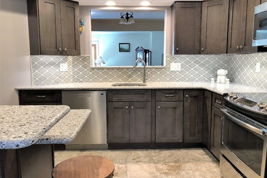 Inspiration for a mid-sized transitional l-shaped eat-in kitchen in Baltimore with an undermount sink, shaker cabinets, grey cabinets, quartz benchtops, grey splashback, porcelain splashback, stainless steel appliances, ceramic floors, a peninsula, grey floor and grey benchtop.