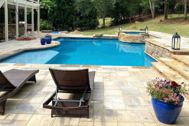 Backyard custom-shaped pool in Atlanta with a hot tub and natural stone pavers.