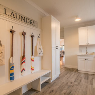 オレンジカウンティの大きいトランジショナルスタイルのおしゃれなランドリールーム (アンダーカウンターシンク、シェーカースタイル扉のキャビネット、白いキャビネット、人工大理石カウンター、白い壁、淡色無垢フローリング、左右配置の洗濯機・乾燥機) の写真