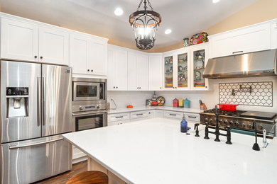 Kitchen - transitional vaulted ceiling kitchen idea in Portland with a farmhouse sink, shaker cabinets, white cabinets, quartz countertops, white backsplash, ceramic backsplash, stainless steel appliances and an island