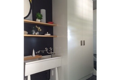 Small contemporary galley dedicated laundry room in Brisbane with a farmhouse sink, flat-panel cabinets, white cabinets, wood benchtops, purple walls, concrete floors and a concealed washer and dryer.