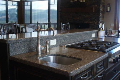 Inspiration for a kitchen remodel in Denver with raised-panel cabinets, dark wood cabinets, granite countertops, stone slab backsplash and an island