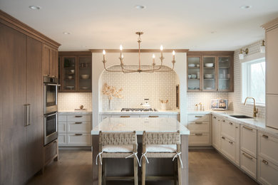 Mid-sized transitional u-shaped medium tone wood floor and brown floor eat-in kitchen photo in Other with an undermount sink, glass-front cabinets, medium tone wood cabinets, solid surface countertops, yellow backsplash, mosaic tile backsplash, paneled appliances, an island and white countertops