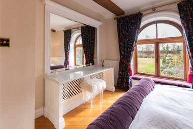 Inspiration for a large contemporary master bedroom in Essex with beige walls, dark hardwood flooring, brown floors and a feature wall.