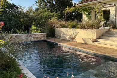 Réalisation d'une piscine arrière design de taille moyenne avec une terrasse en bois.