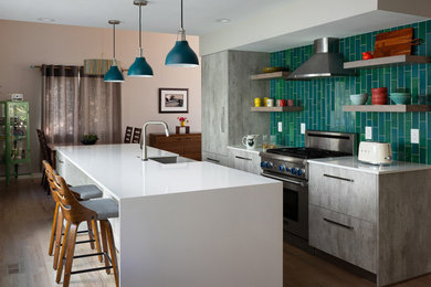 Eat-in kitchen - mid-sized contemporary galley medium tone wood floor and brown floor eat-in kitchen idea in Denver with a farmhouse sink, flat-panel cabinets, gray cabinets, quartz countertops, green backsplash, ceramic backsplash, stainless steel appliances, an island and white countertops