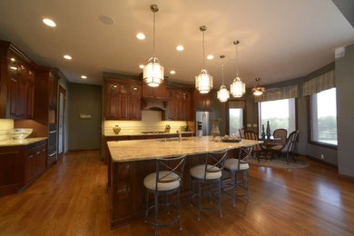 Inspiration for a large transitional medium tone wood floor eat-in kitchen remodel in Other with recessed-panel cabinets, medium tone wood cabinets, granite countertops, beige backsplash, stainless steel appliances and an island