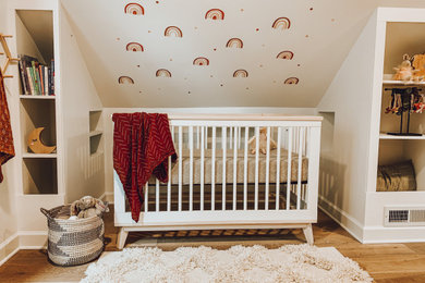 Imagen de habitación de bebé niña vintage de tamaño medio con paredes blancas, suelo de madera clara y suelo beige