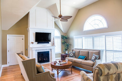 Mid-sized beach style formal and enclosed light wood floor living room photo in Philadelphia with a standard fireplace, a wood fireplace surround, a wall-mounted tv and beige walls