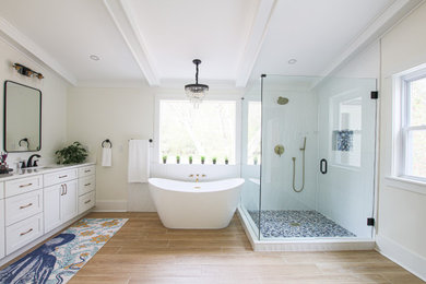 Пример оригинального дизайна: большая главная ванная комната в стиле неоклассика (современная классика) с фасадами в стиле шейкер, белыми фасадами, отдельно стоящей ванной, угловым душем, инсталляцией, белой плиткой, керамической плиткой, бежевыми стенами, полом из керамической плитки, накладной раковиной, столешницей из искусственного кварца, бежевым полом, душем с распашными дверями, белой столешницей, нишей, тумбой под две раковины, встроенной тумбой и балками на потолке