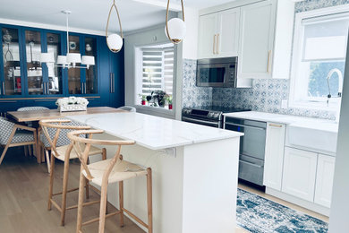 Inspiration for a mid-sized french country u-shaped light wood floor and beige floor eat-in kitchen remodel in Montreal with a farmhouse sink, shaker cabinets, white cabinets, quartz countertops, blue backsplash, porcelain backsplash, stainless steel appliances, an island and white countertops