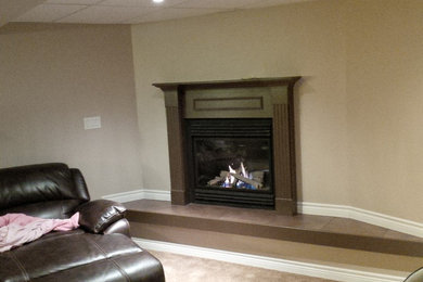 Inspiration for a mid-sized timeless underground carpeted basement remodel in Toronto with beige walls and a standard fireplace