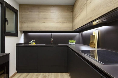 Foto de cocinas en L minimalista pequeña abierta sin isla con salpicadero negro, electrodomésticos negros, suelo de madera clara, suelo beige y encimeras negras