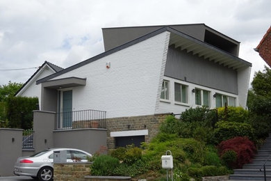 Réalisation d'une façade de maison grise minimaliste de taille moyenne et à un étage avec un revêtement mixte et un toit à deux pans.