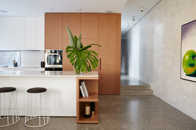 Design ideas for a contemporary galley kitchen in Sydney with flat-panel cabinets, medium wood cabinets, concrete floors, with island, grey floor and white benchtop.