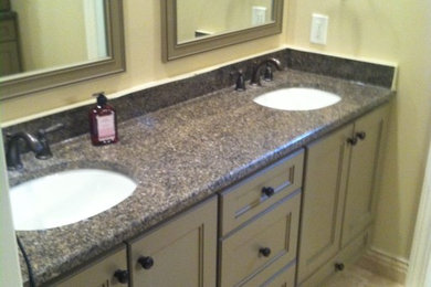Elegant master beige tile and stone tile travertine floor corner shower photo in Cincinnati with an undermount sink, recessed-panel cabinets, medium tone wood cabinets, granite countertops, a one-piece toilet and beige walls