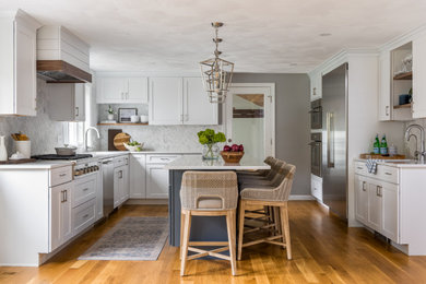 Eat-in kitchen - large traditional l-shaped medium tone wood floor and brown floor eat-in kitchen idea in Boston with a single-bowl sink, shaker cabinets, white cabinets, quartz countertops, white backsplash, marble backsplash, stainless steel appliances, an island and white countertops