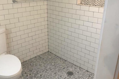 Inspiration for a mid-sized transitional master white tile and subway tile porcelain tile, gray floor and single-sink wet room remodel in Grand Rapids with shaker cabinets, white cabinets, a two-piece toilet, green walls, solid surface countertops, white countertops and a freestanding vanity