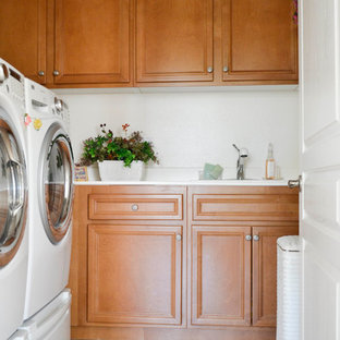 ロサンゼルスの小さい地中海スタイルのおしゃれな洗濯室 (シングルシンク、中間色木目調キャビネット、白い壁、トラバーチンの床、左右配置の洗濯機・乾燥機) の写真