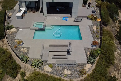 Pool landscaping - large modern backyard concrete paver and rectangular aboveground pool landscaping idea in Los Angeles