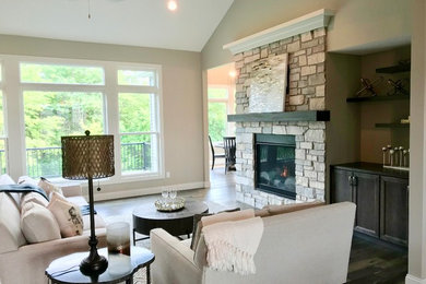 Example of a mid-sized transitional open concept medium tone wood floor and gray floor family room design in Chicago with beige walls, a standard fireplace, a stone fireplace and a tv stand