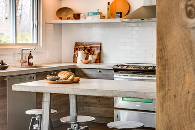 Inspiration for a mid-sized industrial u-shaped porcelain tile enclosed kitchen remodel in Montreal with an undermount sink, flat-panel cabinets, gray cabinets, concrete countertops, white backsplash, ceramic backsplash, stainless steel appliances and an island