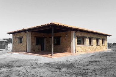 Diseño de fachada de casa beige clásica renovada pequeña de una planta con revestimiento de piedra, tejado a cuatro aguas y tejado de teja de barro