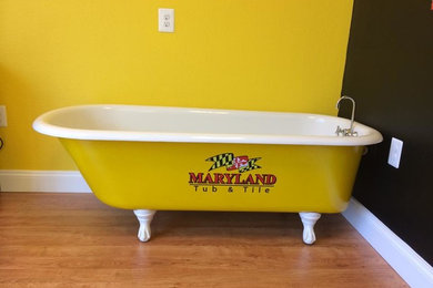 Foto på ett litet funkis badrum, med ett badkar med tassar, gul kakel, gula väggar och ljust trägolv