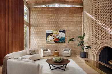 Living room - large 1950s formal light wood floor, brown floor, wood ceiling and brick wall living room idea in Austin with brown walls, a standard fireplace and a brick fireplace