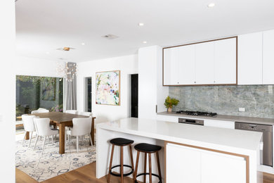Inspiration for a large contemporary l-shaped open plan kitchen in Melbourne with a submerged sink, white cabinets, engineered stone countertops, multi-coloured splashback, porcelain splashback, stainless steel appliances, medium hardwood flooring, an island, white worktops and shaker cabinets.