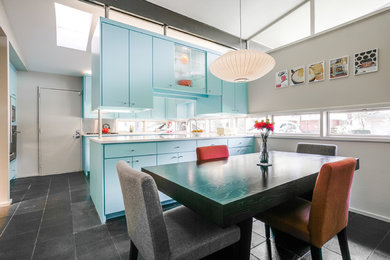 Mid-sized midcentury u-shaped separate kitchen in Dallas with an undermount sink, flat-panel cabinets, blue cabinets, quartz benchtops, window splashback, stainless steel appliances, slate floors and black floor.