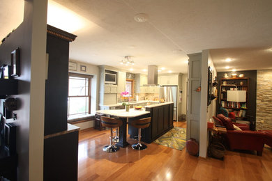 Example of a mid-sized transitional u-shaped medium tone wood floor and brown floor kitchen design in Omaha with an undermount sink, shaker cabinets, white cabinets, quartz countertops, multicolored backsplash, matchstick tile backsplash, stainless steel appliances and an island