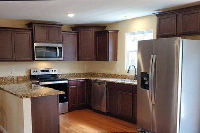 Mid-sized elegant u-shaped eat-in kitchen photo in Other with a double-bowl sink, orange backsplash, granite backsplash, stainless steel appliances and orange countertops