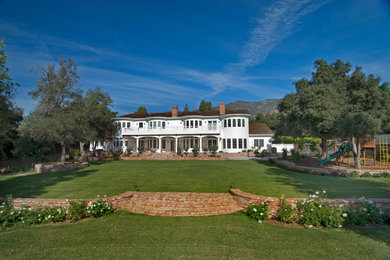 Large elegant white two-story wood house exterior photo in Los Angeles with a hip roof and a shingle roof