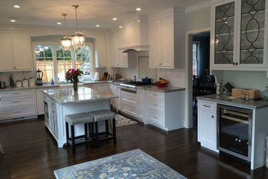Example of a mid-sized transitional l-shaped dark wood floor eat-in kitchen design in San Francisco with a farmhouse sink, beaded inset cabinets, white cabinets, quartzite countertops, white backsplash, subway tile backsplash, stainless steel appliances and an island