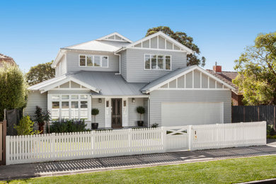Inspiration for a large transitional two-storey grey house exterior in Melbourne with wood siding, a gable roof, a metal roof and board and batten siding.