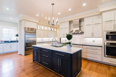 Eat-in kitchen - mid-sized traditional u-shaped light wood floor and brown floor eat-in kitchen idea with a double-bowl sink, flat-panel cabinets, white cabinets, quartz countertops, gray backsplash, stone tile backsplash, stainless steel appliances and an island