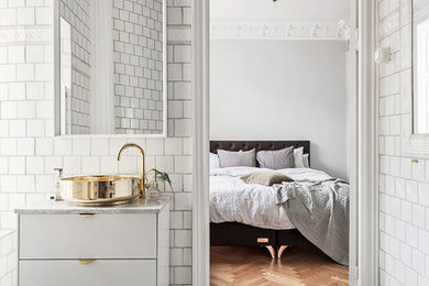 This is an example of a large scandinavian master bathroom in Stockholm with flat-panel cabinets, white cabinets, white tile, ceramic tile, white walls, limestone floors, a vessel sink and marble benchtops.