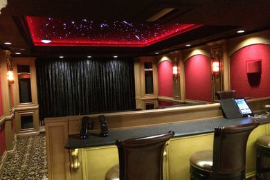 Ejemplo de cine en casa cerrado clásico renovado grande con paredes rojas, moqueta y pantalla de proyección